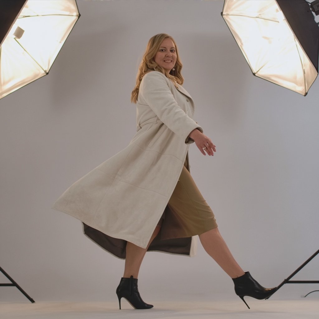 Andrea Florescu, business consultant and fractional leader, in a long white coat walking confidently across a studio backdrop — embodying clarity and decisive technology strategy